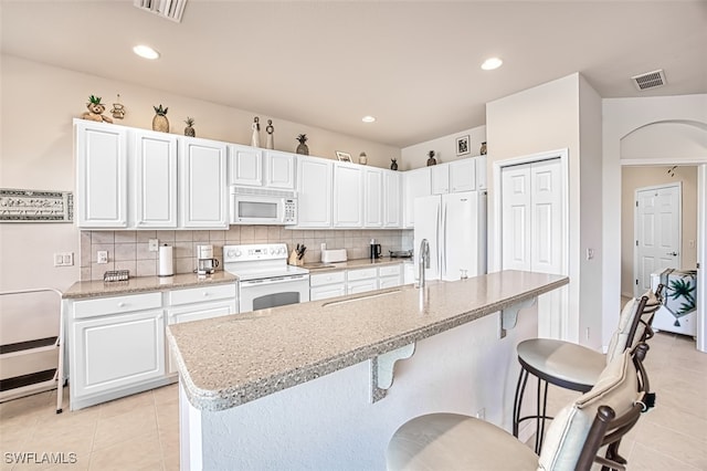 kitchen with white cabinetry, light tile patterned floors, white appliances, and a center island with sink