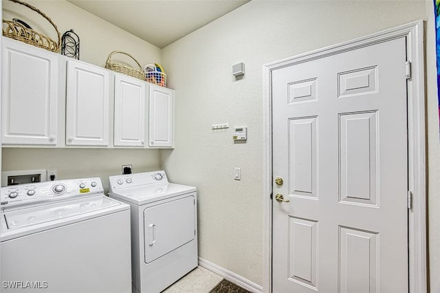 laundry area with cabinets, light tile patterned floors, and washing machine and clothes dryer