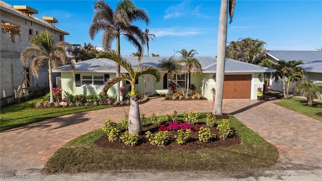 single story home with stucco siding, metal roof, decorative driveway, and a garage