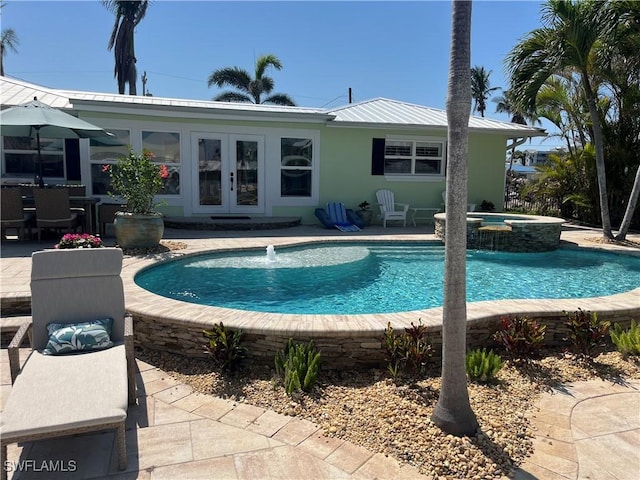 view of swimming pool with french doors, a patio area, and a pool with connected hot tub