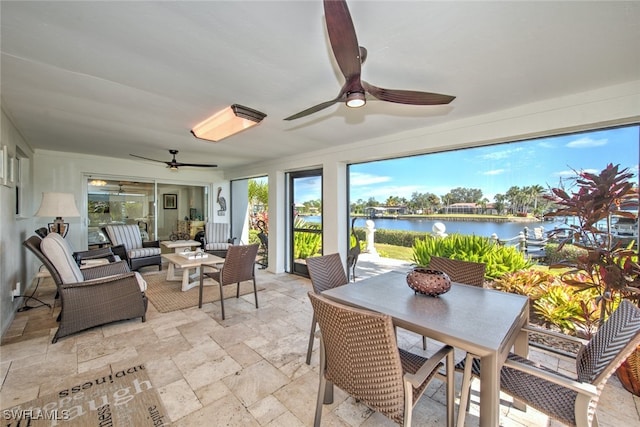 sunroom / solarium featuring ceiling fan and a water view