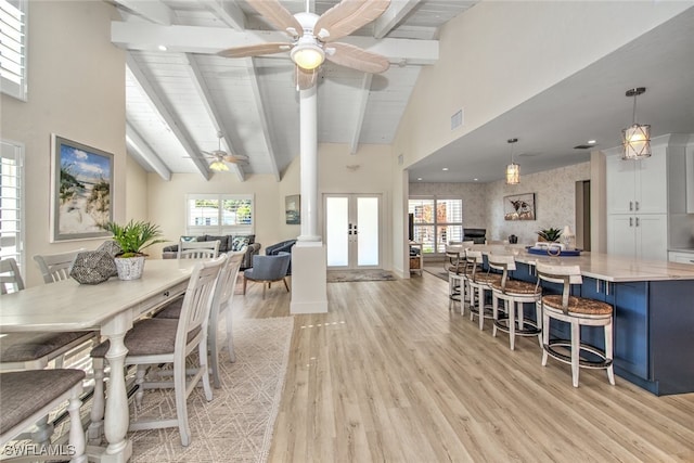 dining room featuring beam ceiling, plenty of natural light, light hardwood / wood-style floors, and french doors