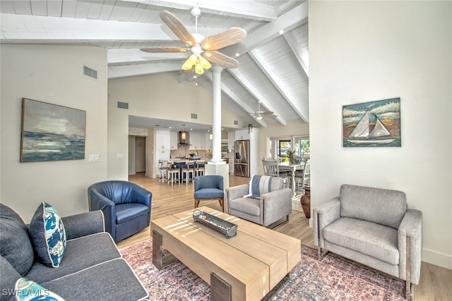 living room featuring hardwood / wood-style flooring, ceiling fan, beam ceiling, and high vaulted ceiling