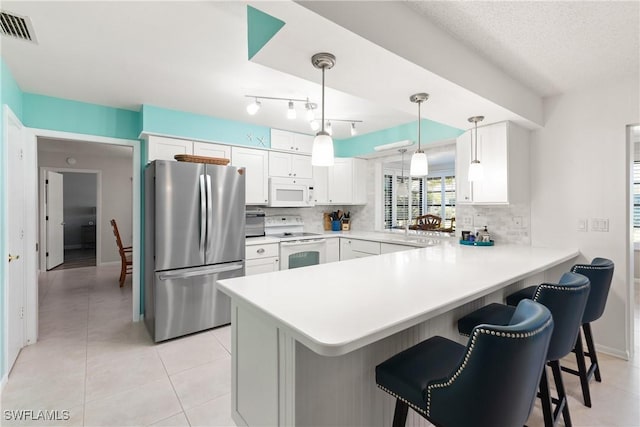 kitchen with a kitchen bar, kitchen peninsula, pendant lighting, white appliances, and white cabinets