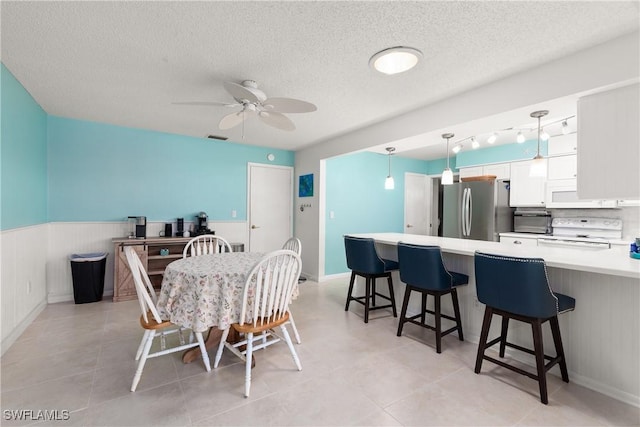 dining space featuring ceiling fan and a textured ceiling