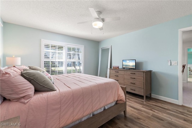 bedroom featuring dark hardwood / wood-style flooring, ceiling fan, and a textured ceiling