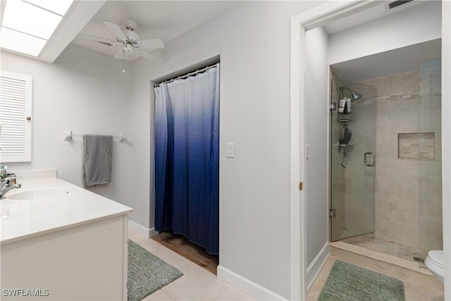 bathroom with a shower with shower door, a skylight, tile patterned flooring, vanity, and ceiling fan