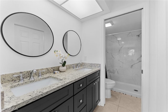 bathroom with tile patterned floors, vanity, toilet, and a tile shower