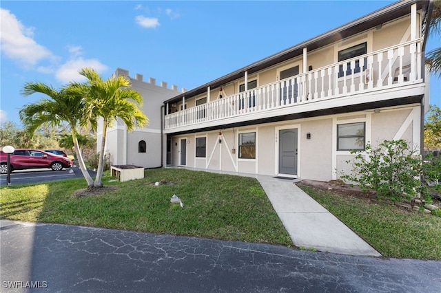 view of front facade featuring a balcony and a front lawn