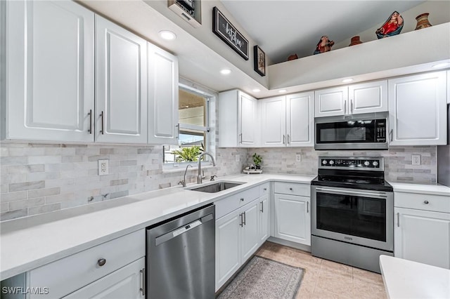 kitchen featuring sink, white cabinetry, light tile patterned floors, stainless steel appliances, and backsplash