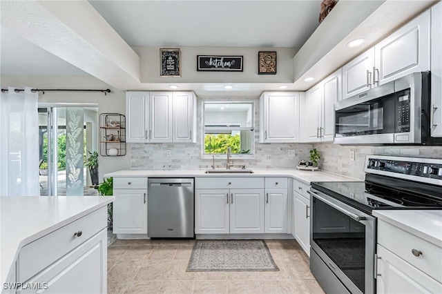 kitchen with white cabinetry, appliances with stainless steel finishes, sink, and decorative backsplash