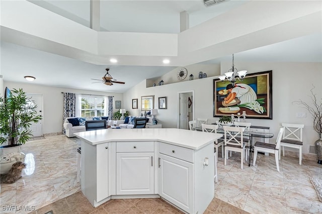 kitchen with white cabinetry, ceiling fan with notable chandelier, high vaulted ceiling, and a kitchen island