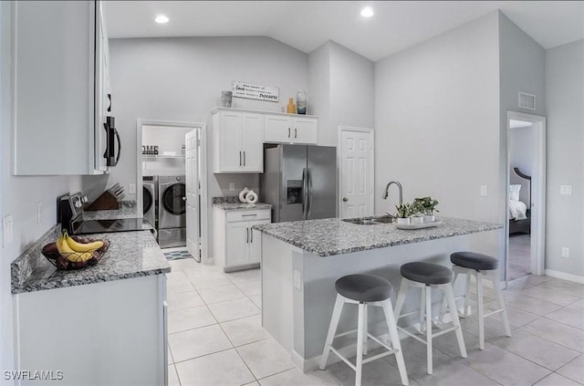 kitchen featuring sink, appliances with stainless steel finishes, white cabinetry, independent washer and dryer, and vaulted ceiling