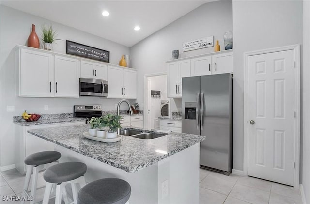 kitchen with sink, light stone counters, appliances with stainless steel finishes, an island with sink, and white cabinets