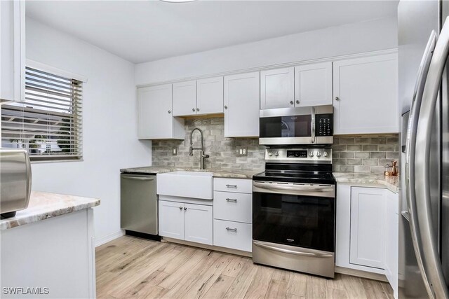 kitchen featuring sink, stainless steel appliances, light hardwood / wood-style floors, and white cabinets