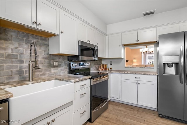 kitchen with stainless steel appliances, visible vents, light wood-style flooring, decorative backsplash, and white cabinetry