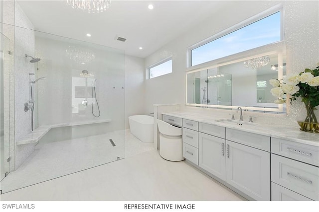 bathroom with a soaking tub, an inviting chandelier, walk in shower, vanity, and recessed lighting