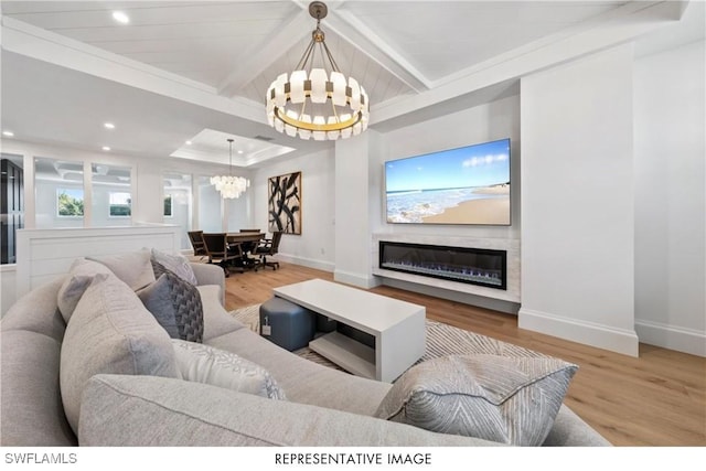 living area with a glass covered fireplace, a notable chandelier, baseboards, and wood finished floors