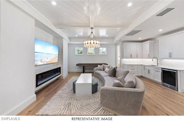 living area featuring light wood-style flooring, a glass covered fireplace, and visible vents