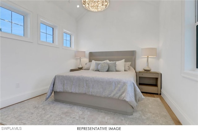 bedroom featuring an inviting chandelier, baseboards, and vaulted ceiling