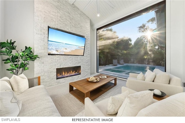 living area with high vaulted ceiling, a stone fireplace, and beamed ceiling