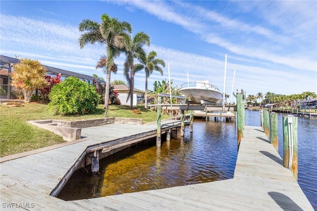 view of dock with a lawn and a water view