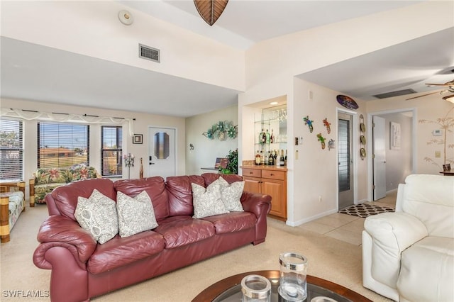 tiled living room with ceiling fan and bar area