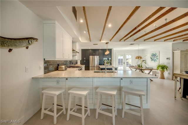 kitchen with pendant lighting, white cabinets, french doors, decorative backsplash, and kitchen peninsula