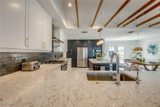 kitchen featuring tasteful backsplash, hanging light fixtures, stainless steel appliances, light stone countertops, and white cabinets