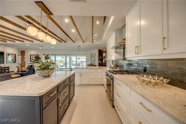 kitchen with hanging light fixtures, sink, white cabinets, and stainless steel range