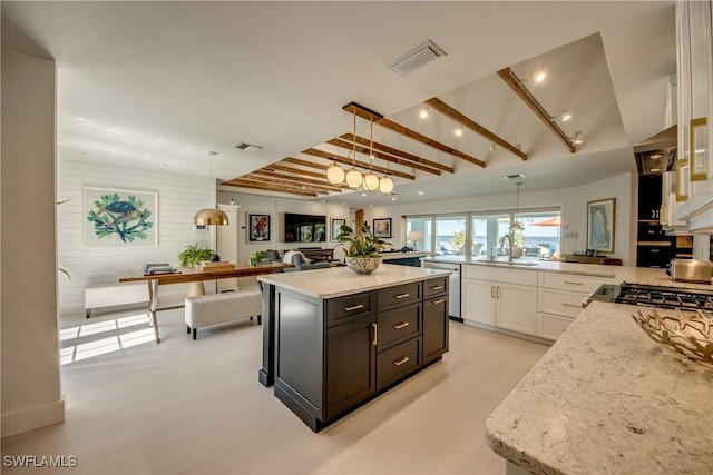 kitchen with a kitchen island, wooden walls, decorative light fixtures, white cabinets, and beam ceiling