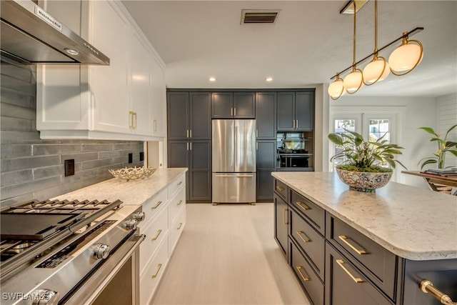 kitchen featuring light stone counters, appliances with stainless steel finishes, decorative backsplash, and white cabinets