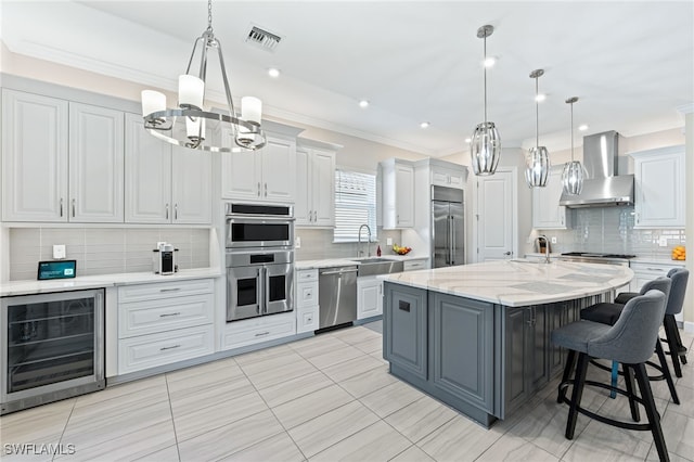 kitchen featuring appliances with stainless steel finishes, sink, wine cooler, a kitchen island with sink, and wall chimney range hood