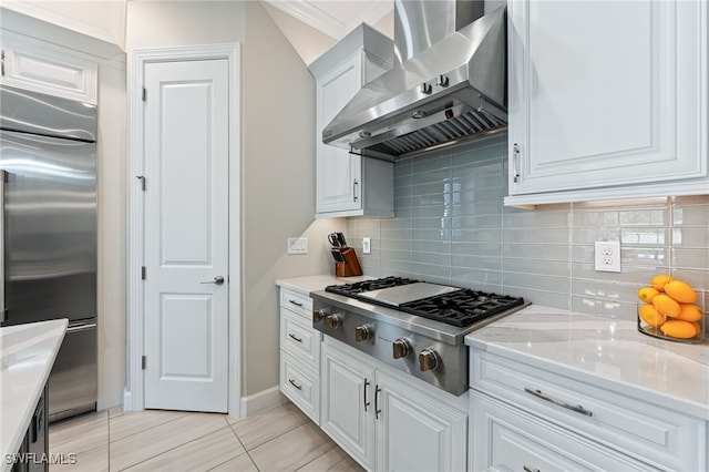 kitchen with tasteful backsplash, ventilation hood, appliances with stainless steel finishes, light stone countertops, and white cabinets