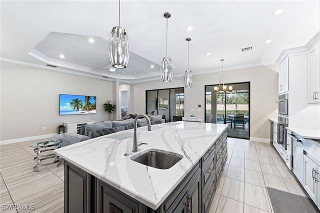 kitchen featuring white cabinetry, sink, an island with sink, and a raised ceiling