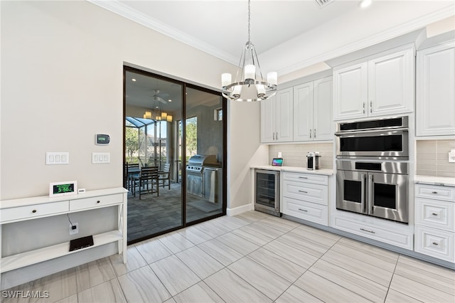 kitchen with white cabinetry, tasteful backsplash, a notable chandelier, beverage cooler, and stainless steel double oven