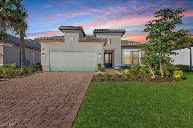 mediterranean / spanish house featuring a garage and a lawn