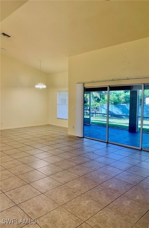 unfurnished room featuring an inviting chandelier, light tile patterned floors, and lofted ceiling