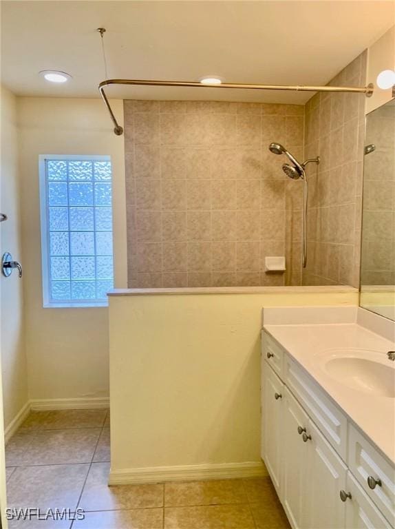 bathroom with tile patterned flooring, vanity, and tiled shower