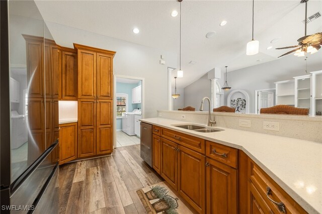 kitchen featuring pendant lighting, sink, stainless steel appliances, independent washer and dryer, and light wood-type flooring