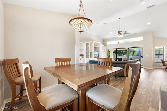 dining space with visible vents, baseboards, a ceiling fan, lofted ceiling, and light wood-style flooring