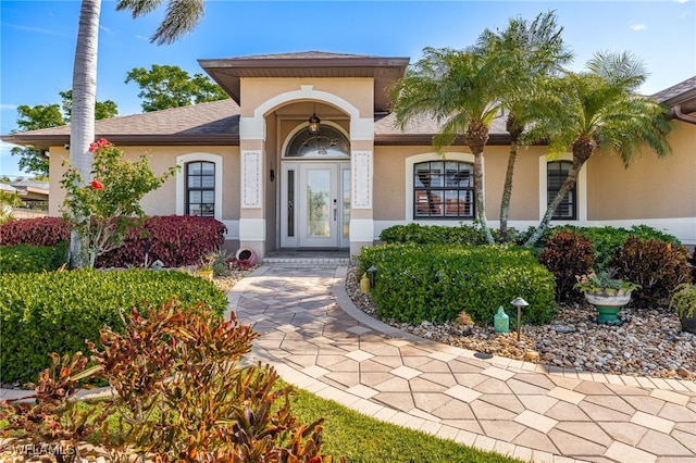 entrance to property with a shingled roof and stucco siding