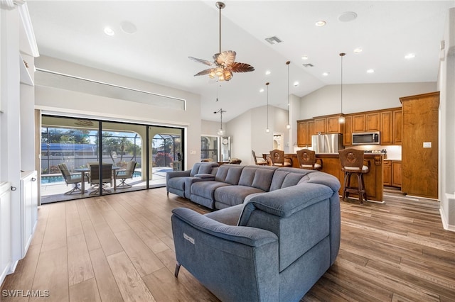 living room with high vaulted ceiling, visible vents, light wood-style flooring, and a ceiling fan