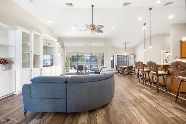 living room with hardwood / wood-style floors, high vaulted ceiling, and ceiling fan