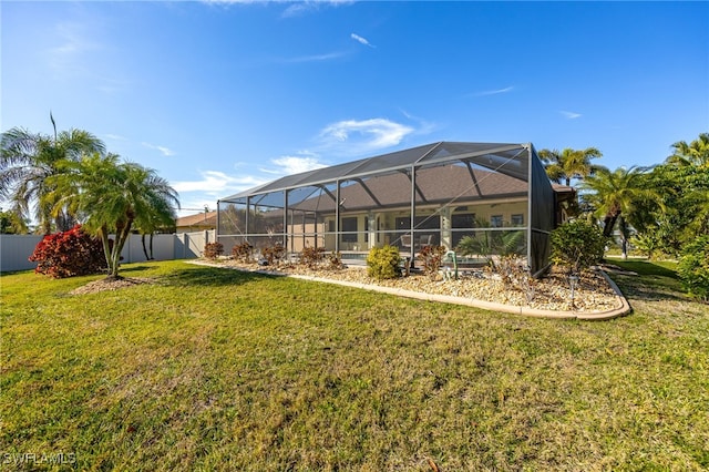 back of property with a yard, a lanai, and fence