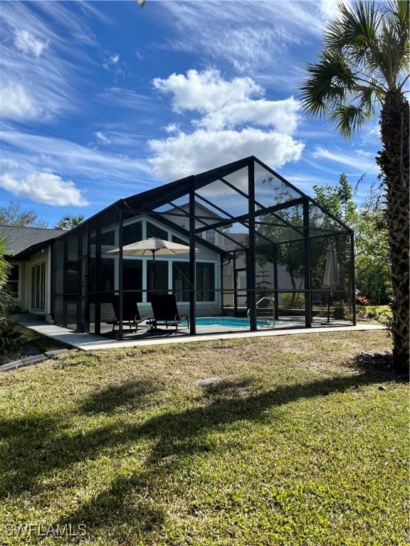 back of property with a lanai, a lawn, and a patio area