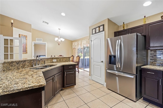 kitchen featuring sink, decorative light fixtures, vaulted ceiling, dark brown cabinets, and stainless steel fridge