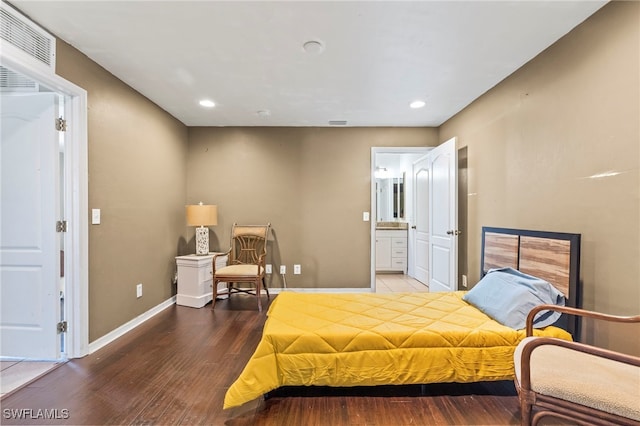 bedroom with connected bathroom and hardwood / wood-style floors