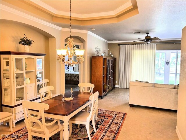 dining room featuring crown molding, a raised ceiling, ceiling fan with notable chandelier, and light tile patterned floors