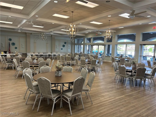 dining area featuring light wood-style flooring, a high ceiling, coffered ceiling, beamed ceiling, and an inviting chandelier